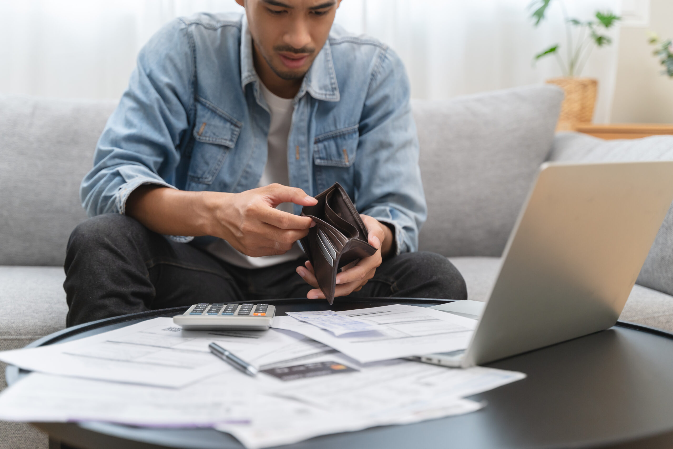 Young man opening empty wallet